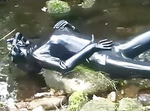 Outdoor walk in the wood and river bath full encased in black latex catsuit and rubber gas mask