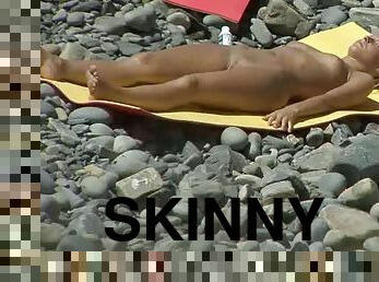 Stunning skinny brunette is lying on the stones