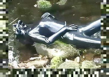 Outdoor walk in the wood and river bath full encased in black latex catsuit and rubber gas mask