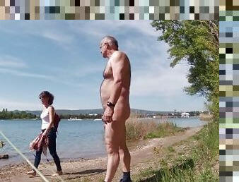 Naked in front of the dressed on the shore of the lake