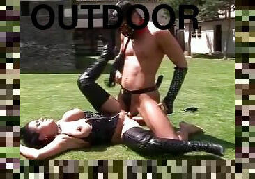 Leather mistress fucks her slave outdoors