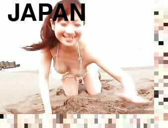 Japanese bikini girl plays in the sand on the beach