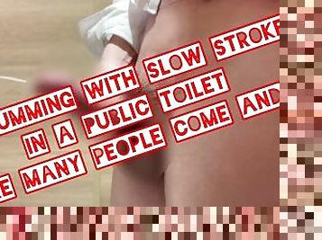 The cumming with slow strokes in a public toilet where many people come and go.